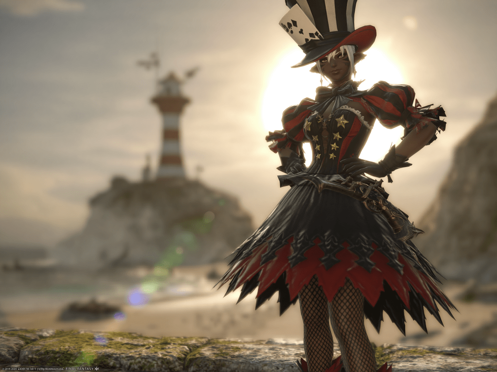 A character in a striking black and red costume with a tall hat stands on a rocky beach, with a lighthouse in the background and the sun shining brightly behind them.